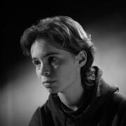 A portrait photograph of a young man in a hoodie. The photograph is in black and white.